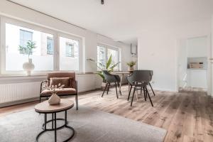 ein weißes Wohnzimmer mit Stühlen und einem Tisch in der Unterkunft *MODERN & MINIMALISTIC* Design-Apartment I Stadtmitte in Wesel