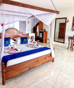 een slaapkamer met een groot bed met een baldakijn bij Karibu Beach Resort in Pongwe