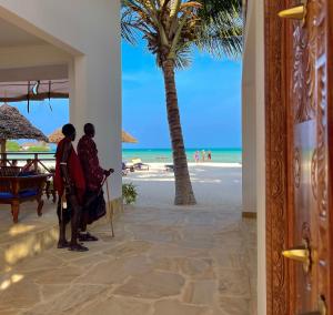 two people standing on the beach looking at the ocean at Karibu Beach Resort - Adults Only in Pongwe