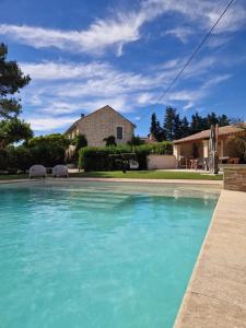 a pool of blue water in front of a house at La Bastide des Arts in Saumane-de-Vaucluse