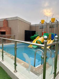 una piscina con tobogán y un parque infantil en استراحة زهرة الاماكن (1), en Yeda