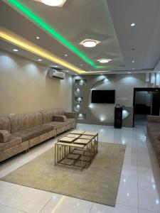 sala de estar con sofás, mesa y TV en استراحة زهرة الاماكن (1), en Yeda