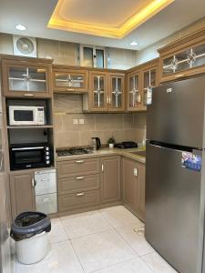 eine Küche mit Holzschränken und einem Kühlschrank aus Edelstahl in der Unterkunft استراحة زهرة الاماكن (1) in Dschidda