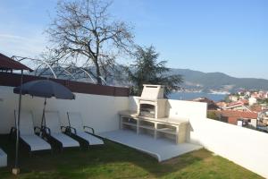 eine Terrasse mit 2 Stühlen, einem Tisch und einem Sonnenschirm in der Unterkunft Casa en Chapela, al lado de Vigo y con vistas a la Ría in Redondela