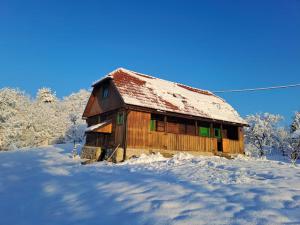 una antigua casa de madera con nieve en el suelo en Bakina iža, en Duga Resa