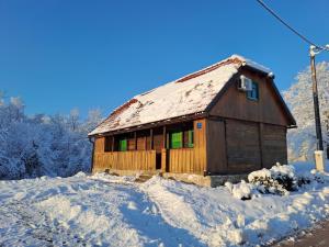 una pequeña casa de madera con nieve en el suelo en Bakina iža, en Duga Resa