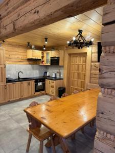 a dining room with a wooden table and a kitchen at Orawska Knieja 2.0 in Lipnica Wielka