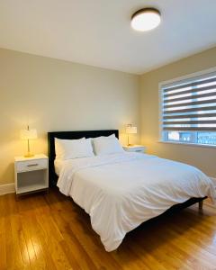a bedroom with a large white bed with two night stands at Mid Century Modern Home Close to HSC Polo Park Mall in Winnipeg
