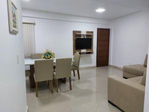 a living room with a table and chairs and a television at Apartamento completo e bem localizado in Vitória da Conquista
