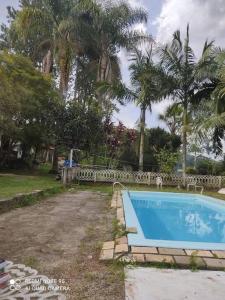 摩基達斯克魯易斯市的住宿－Sítio Nosso Cantinho，棕榈树庭院内的游泳池