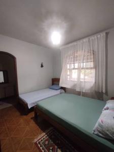 1 dormitorio con 2 camas y ventana en Sítio Nosso Cantinho, en Mogi das Cruzes