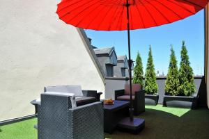 a patio with a red umbrella and chairs and a table at Hotel des Alpes in Geneva