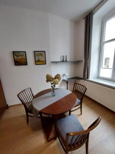 a dining room with a table with chairs and a vase with flowers at Apartament Kamienna Gora in Kamienna Góra