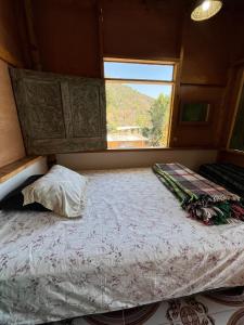 Cama en habitación pequeña con ventana en Casa Madera, en San Marcos La Laguna