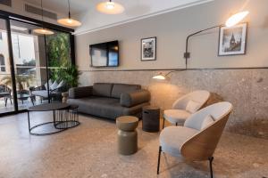 a living room with a couch and chairs and tables at The Londoner Hotel St. Julian's in St. Julianʼs