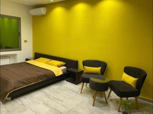 ein Schlafzimmer mit einem Bett, 2 Stühlen und einer gelben Wand in der Unterkunft Villa avec piscine et Jacuzzi Tunis in Mornag