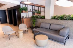 a lobby with a couch and chairs and plants at The Londoner Hotel St. Julian's in St. Julianʼs