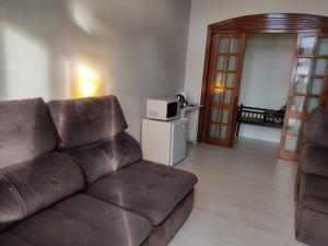 a living room with a brown couch and a microwave at Nascer do Sol - Edelweiss in Nova Petrópolis