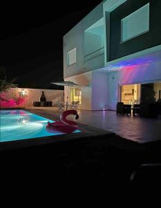MornagにあるVilla avec piscine et Jacuzzi Tunisの夜間のスイミングプール付きハウス