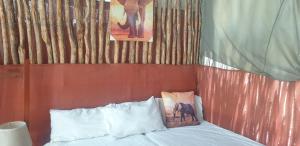 a bed with two pillows and a picture of an elephant at Paradise Camp Game Lodge in Groutfontein