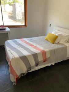 a bedroom with a bed with a colorful blanket on it at Casa en parcela Curacavi in Curacaví