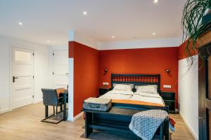 een slaapkamer met een oranje muur, een bed en een bureau bij Klooster Achthuizen in Achthuizen