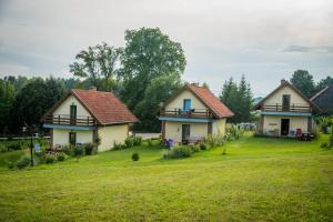 twee huizen op een grasveld met bomen op de achtergrond bij Domki na Mazurach Kurka Wodna in Mikołajki