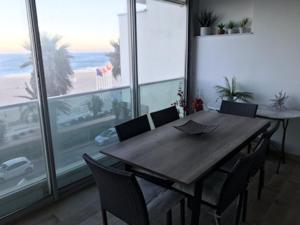 a wooden table and chairs in a room with a window at Appartement face à la mer - 6 à 8 personnes - Canet en Roussillon in Canet-en-Roussillon
