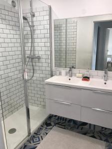 y baño blanco con lavabo y ducha. en Appartement face à la mer - 6 à 8 personnes - Canet en Roussillon, en Canet-en-Roussillon