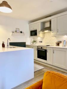 a kitchen with white cabinets and an orange couch at Boutique Chapel Apartment within City Walls in Chester