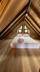 białe łóżko na poddaszu z drewnianą podłogą w obiekcie Adalar Garden Bungalov w mieście Kartepe