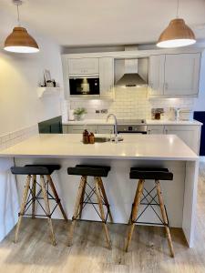 a kitchen with a large white island with two bar stools at Boutique Chapel Apartment within City Walls in Chester