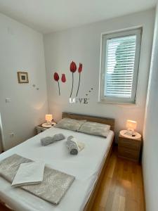 a bedroom with a white bed with flowers on the wall at Apartment Tena in Novalja
