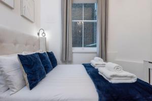 a white bed with blue pillows and towels on it at Beautiful 1 Bed Flat close to Regents Park in London