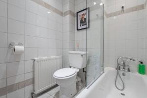 a white bathroom with a toilet and a bath tub at Beautiful 1 Bed Flat close to Regents Park in London