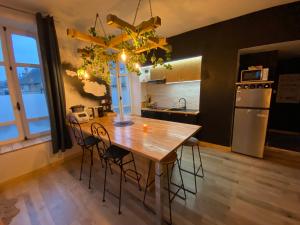 a kitchen with a wooden table with chairs and a refrigerator at - Le backpacker - logement atypique et spacieux en résidence avec ascenseur in Nevers