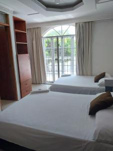 a bedroom with two beds and a large window at Hotel Sierra Nevada B&B SAS in Valledupar