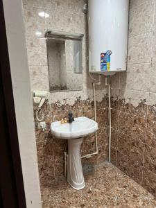 a bathroom with a white sink and a mirror at Ilhombek Guest House Hotel in Tashkent