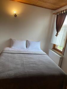 un letto con cuscini bianchi in una camera da letto con finestra di Sakli Kosk Kartepe a Kartepe