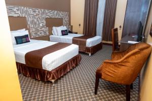 a hotel room with two beds and a chair at The Country Inn by Smart Haven in Kigali