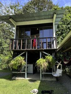 un hombre parado en el balcón de una casa en Casa Morpho Uvita Guesthouse, en Uvita