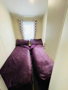 a small room with two beds in front of a window at Water Sky Getaways 3-bedroom caravans at Durdle Door in Wareham