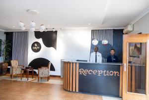 two people standing at the reception desk of a restaurant at The Country Inn by Smart Haven in Kigali