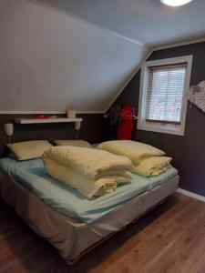 um quarto com uma cama com almofadas e uma janela em Rorbu i Austevoll med 3 soverom og mulighet for båtleie em Kolbeinsvik