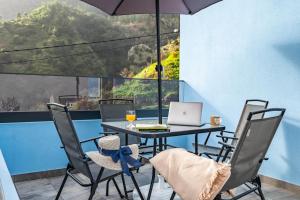 a table with an umbrella and a laptop on a balcony at AGUIAR´S VILLAGE in Ribeira Brava