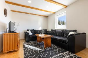 a living room with a black couch and a tv at Vikendica Bjelašnica Lukavac in Bjelašnica