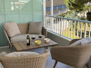 eine Terrasse mit einem Tisch, 2 Stühlen und einer Flasche Wein in der Unterkunft Céntrico apartamento Playa de San Juan Alicante in Alicante