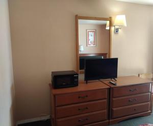 a room with a dresser with a television and a mirror at American Motel in San Antonio