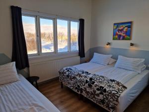 a bedroom with two beds and a large window at Gauksmýri guesthouse in Hvammstangi