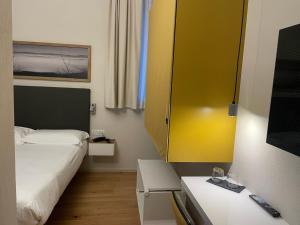 um pequeno quarto com uma cama e um armário amarelo em Albergo Centrale em Lamezia Terme